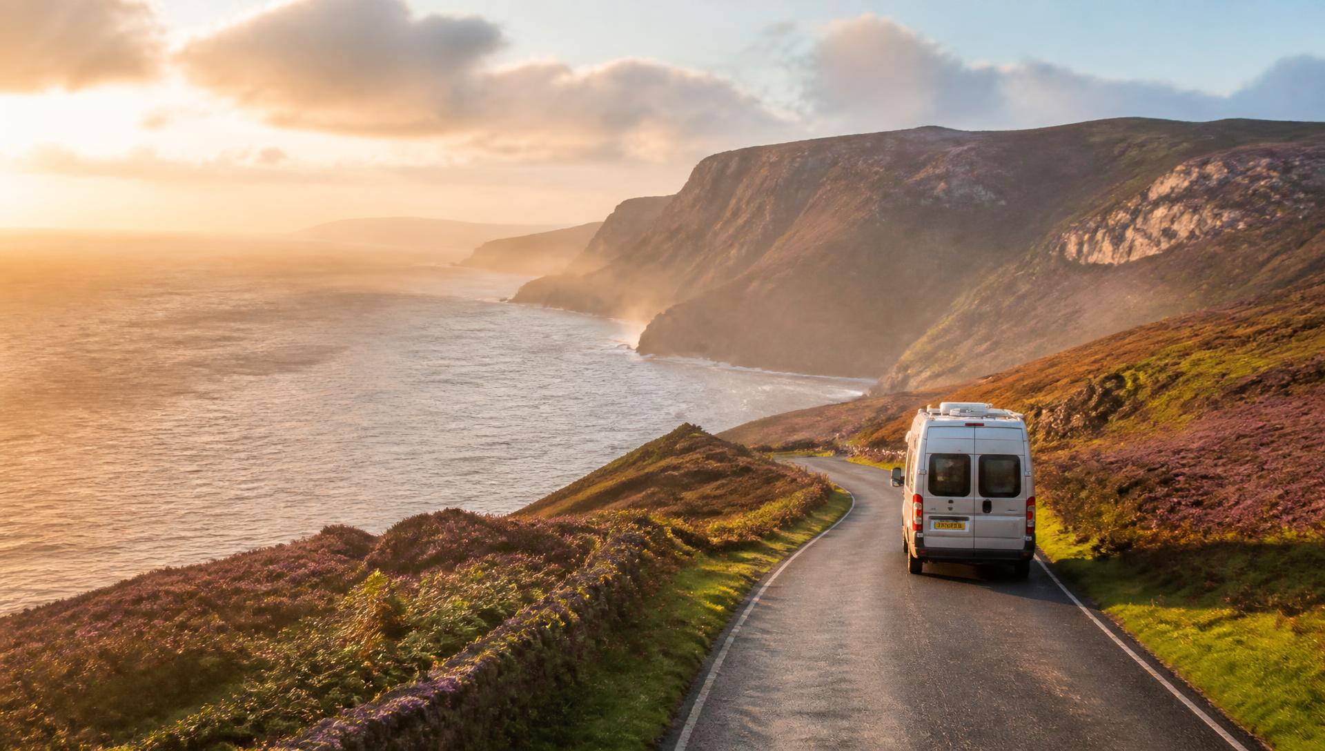 A campervan on a coastal road above the Atlantic at sunset